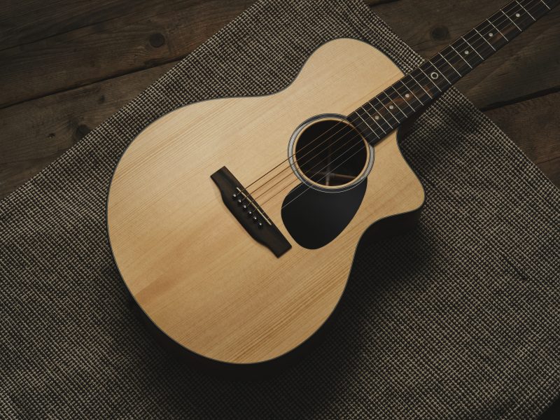 Studio photo of a Martin SC-10E acoustic guitar on a rug and wooden floor