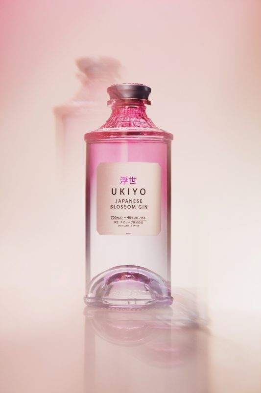 Studio photograph of Ukiyo Blossom Gin on a pink and orange gradient background